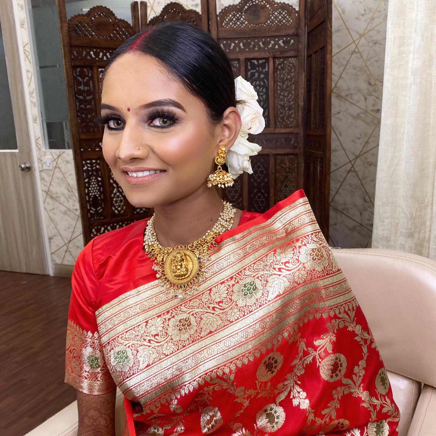 Silk saree bridal makeup Bride in a red and gold Banarasi silk saree with a gold temple necklace, sindoor, smoky eyes and white flowers in her bun